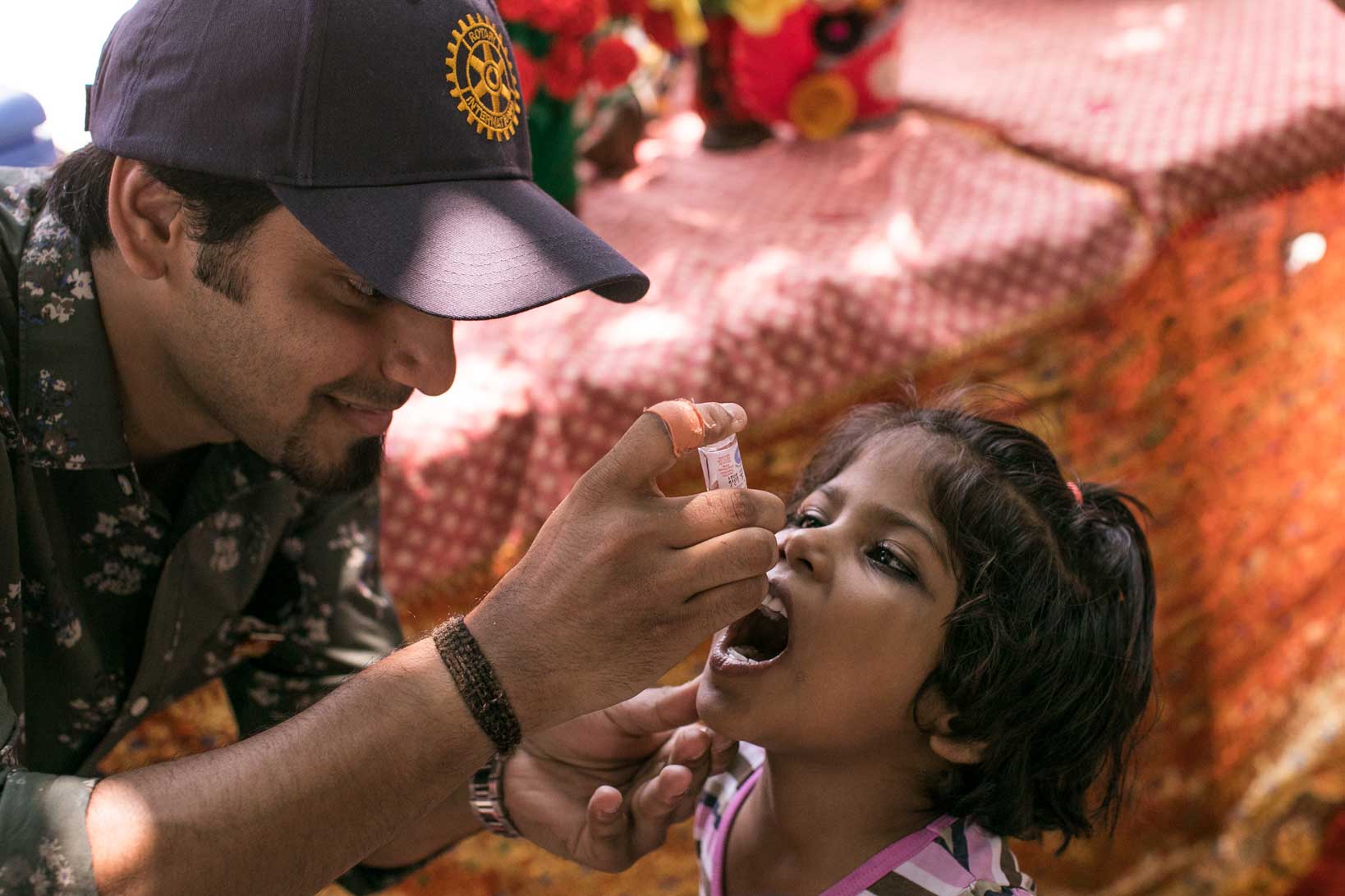 Rotarian giving oral polio vaccine to child in India